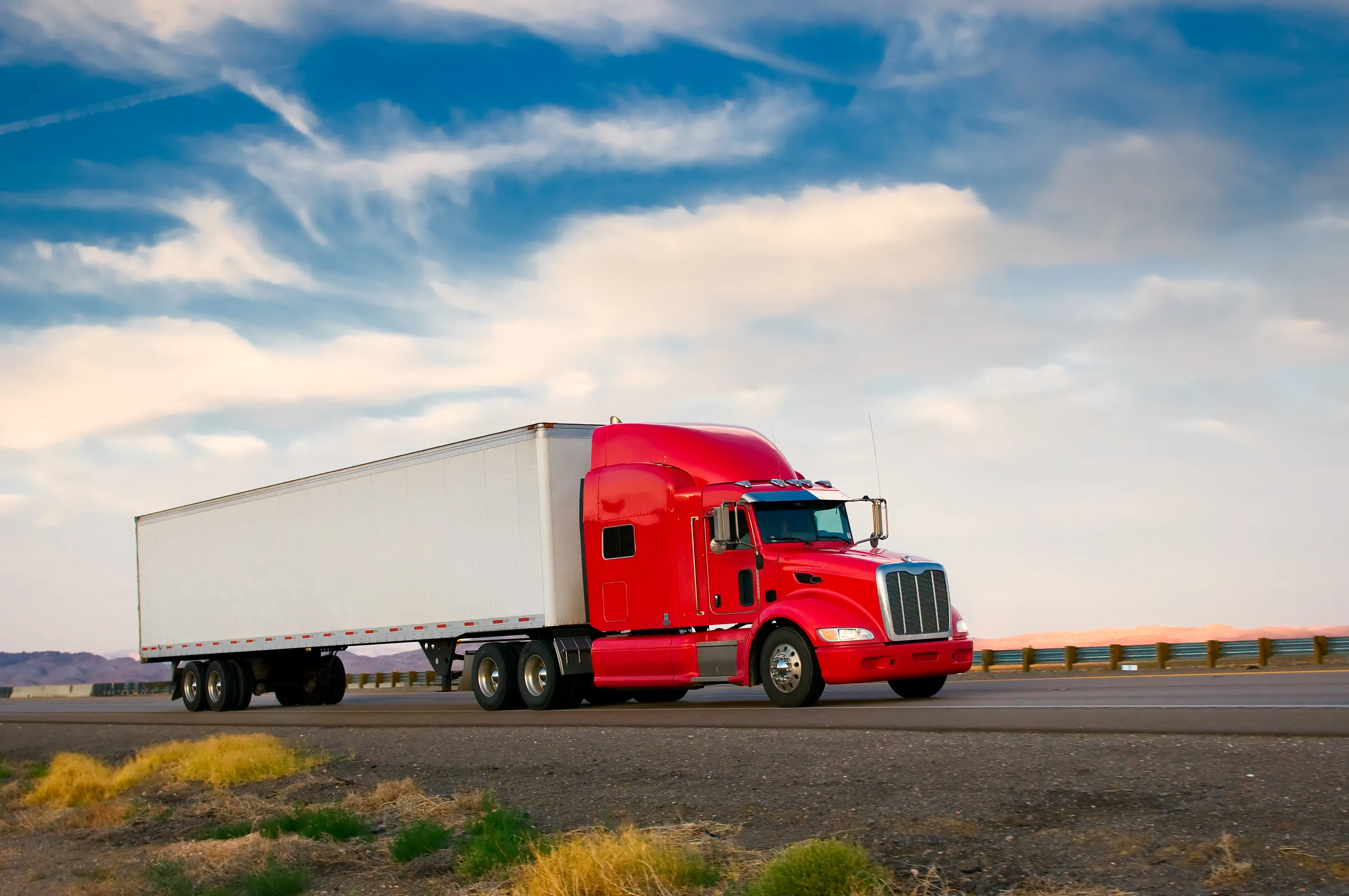 White semi truck pulling dry van trailers on a summer highway